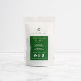 A white package of Evermill Organic Red Pepper Flakes Refill is placed on a marble surface. The front label highlights the savory heat with tasting notes like a sweet aroma and red pepper cornpops. Weighing in at 1.2 oz (34 g), it's perfect for adding to your spice collection and enhancing pizza, pasta, and vegetables.